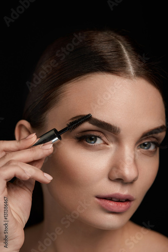 Beautiful Woman Brushing Eyebrows With Brush. Beauty photo