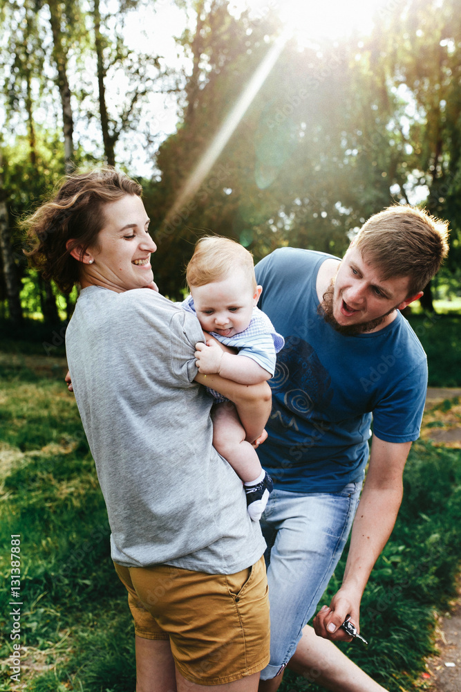 Fototapeta premium Young family, mother father and baby son happy posing in park