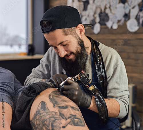 Canvas Print Tattoo master in black gloves, tattoo on the skin of black ink tattoo of his client in the salon