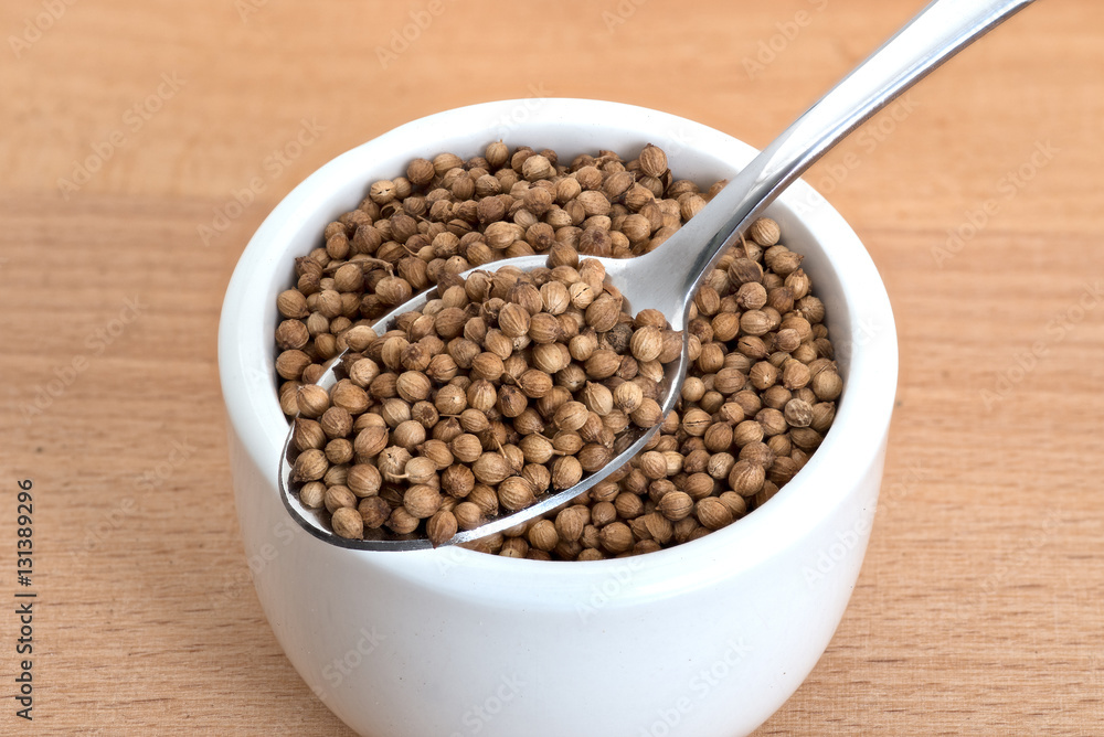 Coriander seeds spoon and in small white bowl Coriander seeds spoon and in small white bowl