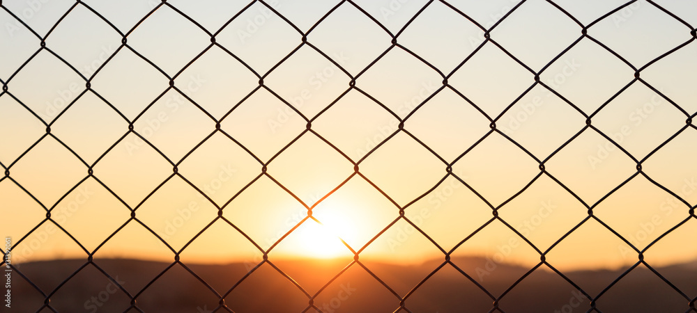Fototapeta premium Wire mesh fence on a sunset background