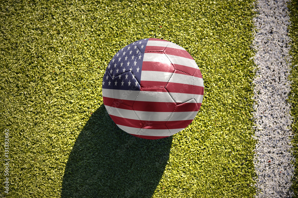 Obraz premium football ball with the national flag of united states of america lies on the field