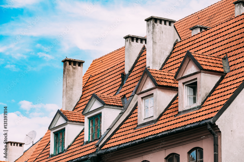 Riga Latvia. Mansard Tile Roof With Four Gable Fronted Dormer Windows On The Old Building Under Blue Sky