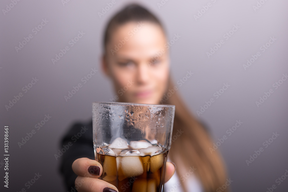Young woman holding fresh Cola with ice cubes. isolated gray.