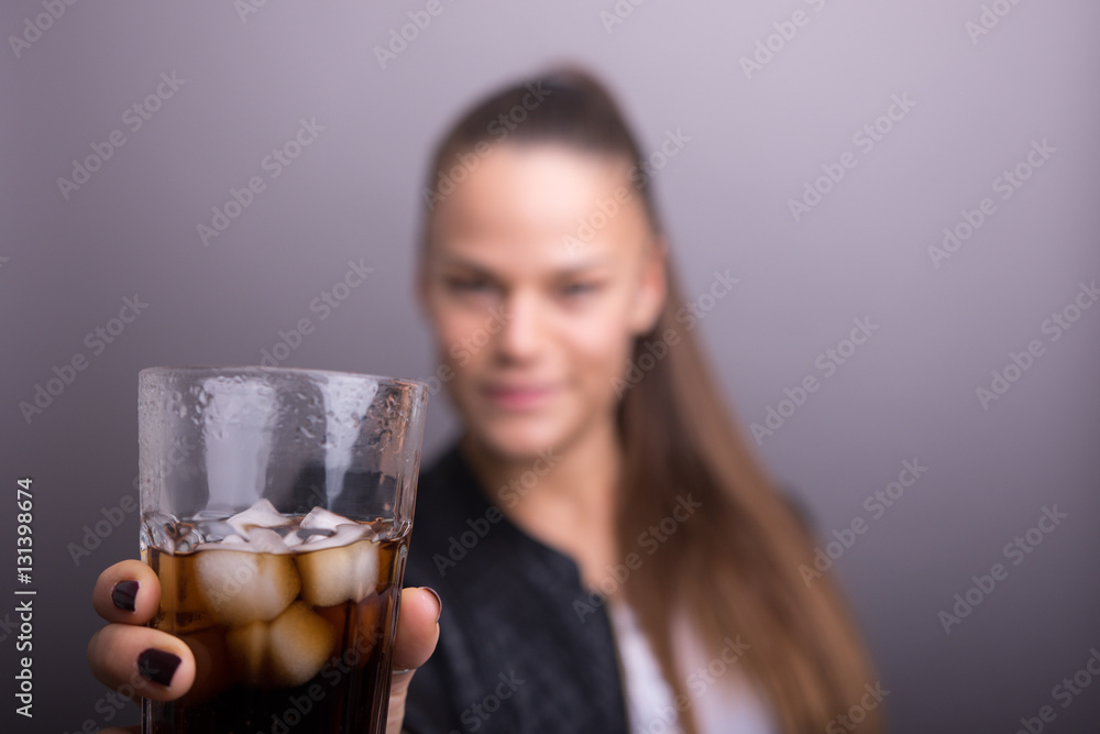 Young woman holding fresh Cola with ice cubes. isolated gray. Young woman holding fresh Cola with ice cubes. isolated gray.