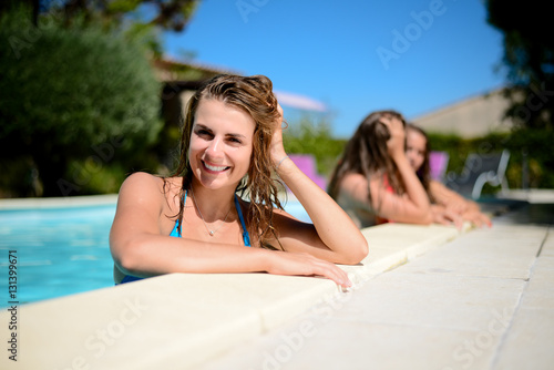 portrait of beautiful young woman in the poolside of a resort swimming pool during summer holiday