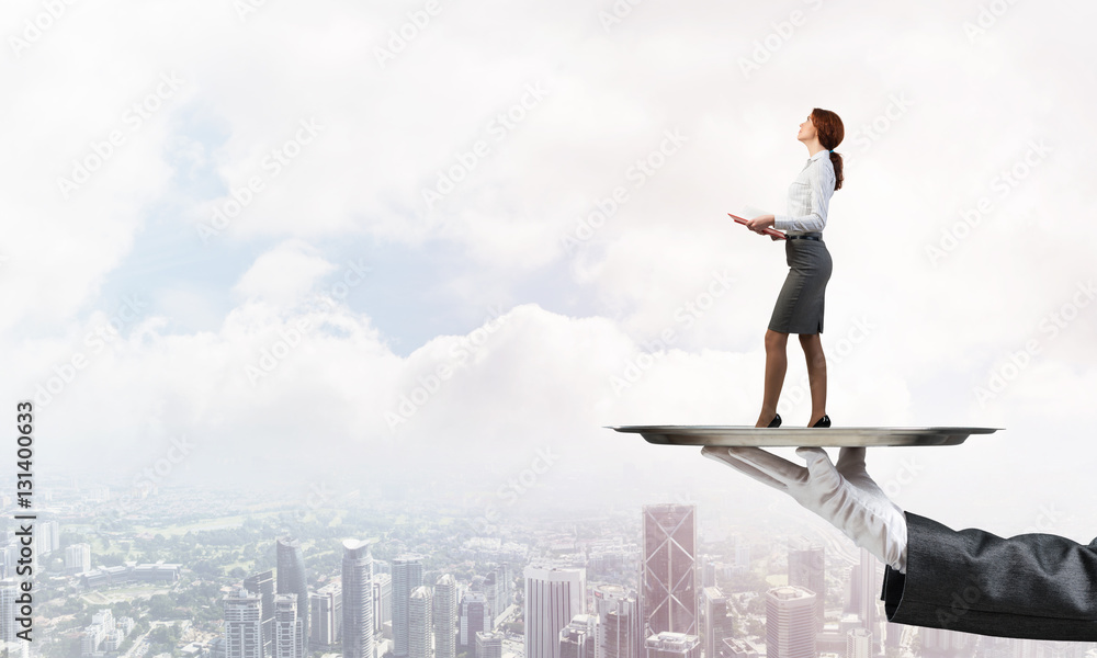 Attractive businesswoman on metal tray with red book in hands against cityscape background Attractive businesswoman on metal tray with red book in hands against cityscape background