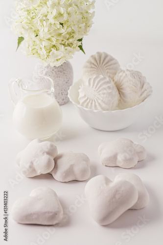 On a white background cakes, desserts, sweets, milk, flowers. Dairy products and sweets in the high key. Studio light. Place for text.