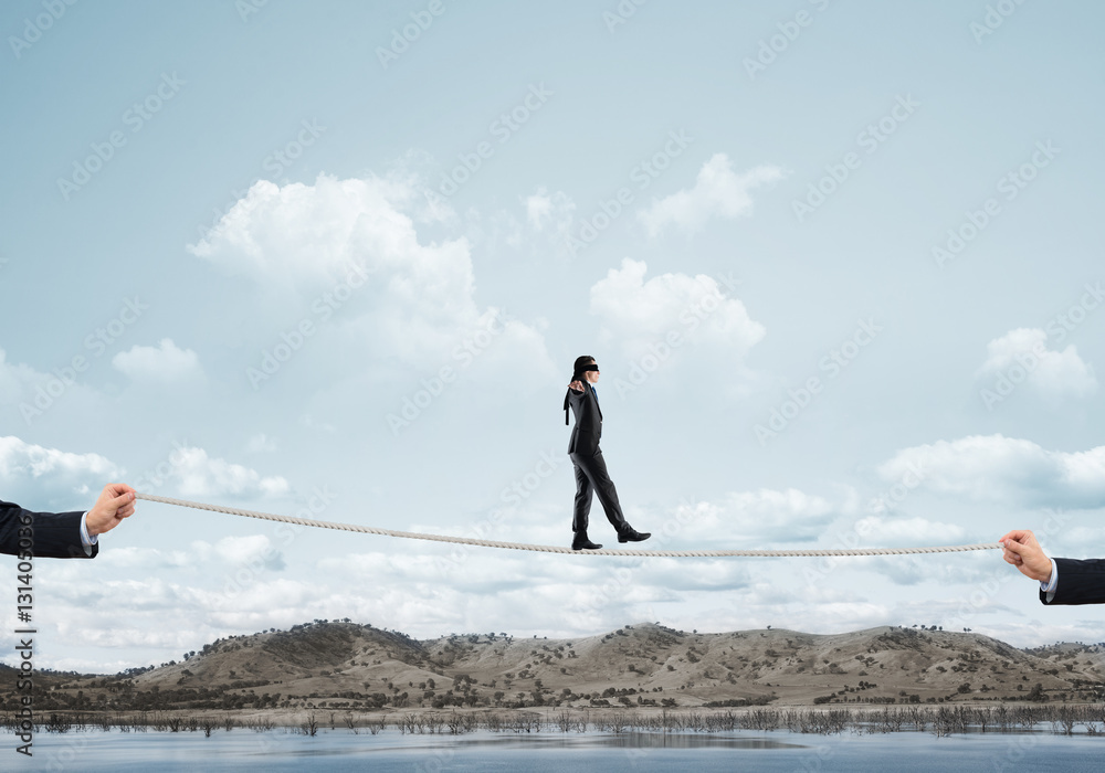 Business concept of risk support and assistance with man balancing on rope Business concept of risk support and assistance with man balancing on rope