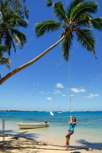 Young woman swinging on a rope swing at Pangaimotu island near T