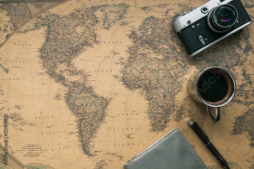 Fotografie Vintage Camera, Notebook, Pen, Metal Coffee Cup on Retro World Map