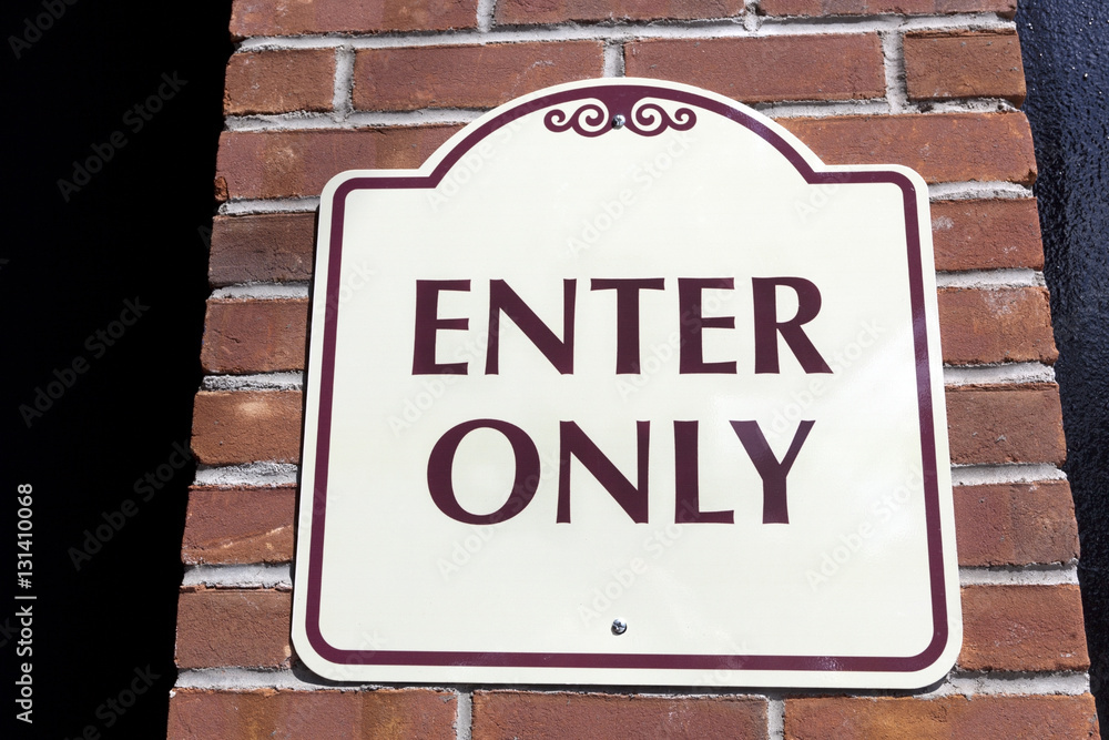 ENTER ONLY sign attached to brick wall. ENTER ONLY sign attached to brick wall.