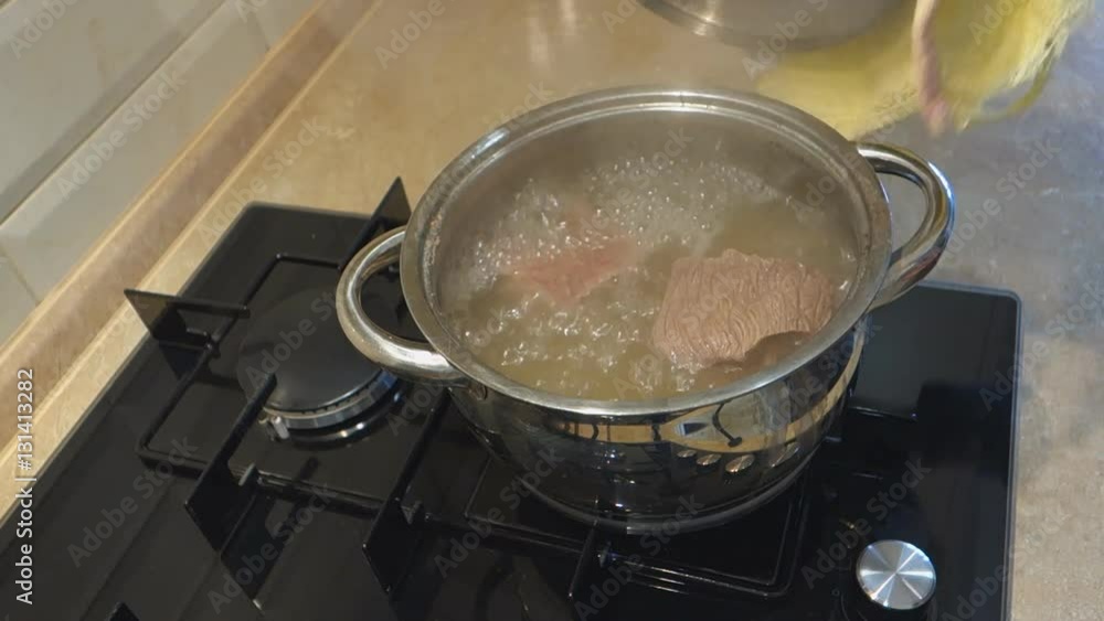 man comes to a gas stove and opens with a towel cover the pan with meat man comes to a gas stove and opens with a towel cover the pan with meat