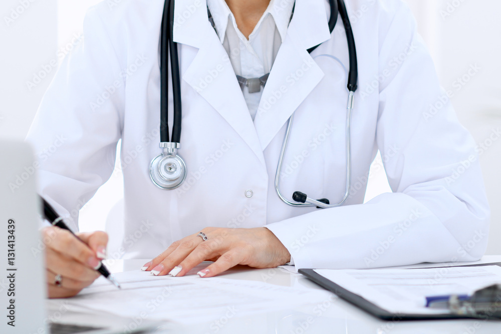 Female doctor at the table and filling up medical form. Medicine and health care concept. Female doctor at the table and filling up medical form. Medicine and health care concept.