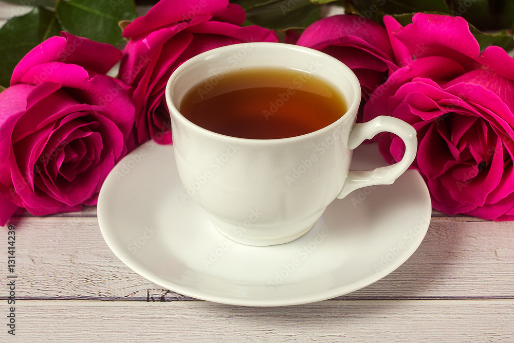 Romantic St Valentine's setting with tea cup and red roses Romantic St Valentine's setting with tea cup and red roses