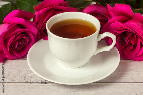Romantic St Valentine's setting with tea cup and red roses