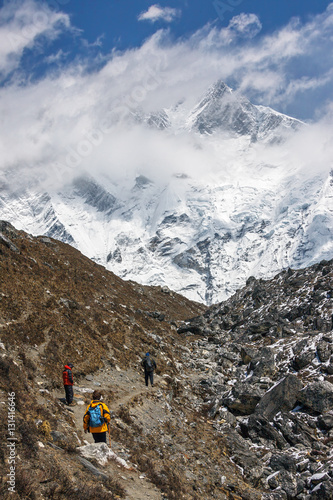 Tourists on the track in the valley Chhukung. On background Lhotse peak (8516 m) in the clouds - Everest region, Nepal, Himalayas photo