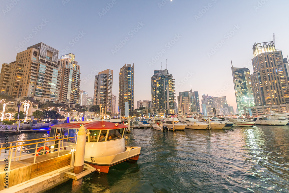 Sunset in Dubai Marina. Buildings reflections over artificial ca