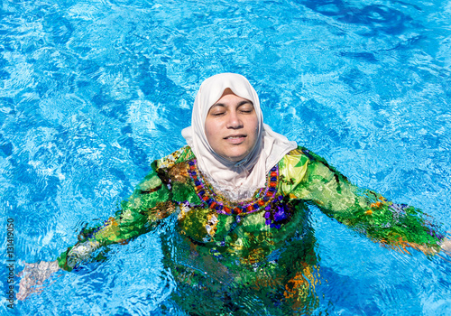 Muslim Arabic woman with burkini in pool photo