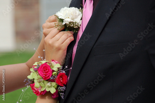 Billede på lærred Young woman pins lapel coursage onto prom date