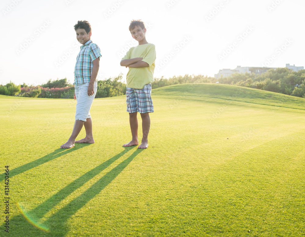 Kids on beautiful green meadow with long shadows