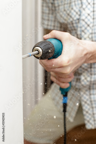 Man drilling a hole in a wooden the door in a room