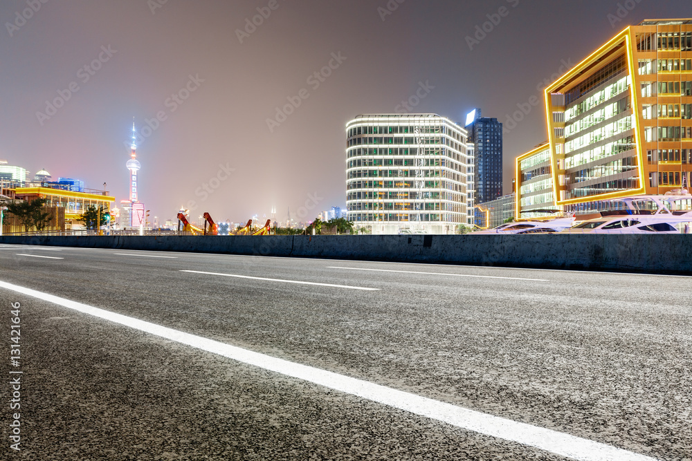 Asphalt road and modern cityscape at night in Shanghai