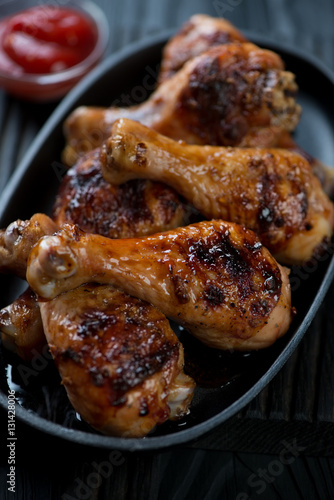 Closeup of barbecued chicken legs served in a frying pan