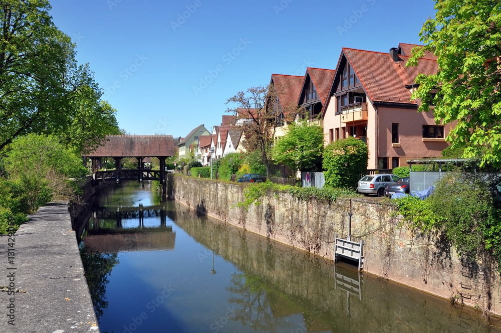 Ancient blocked residential building, located along the water channel and a pedestrian bridge. Bietigheim, Germany.