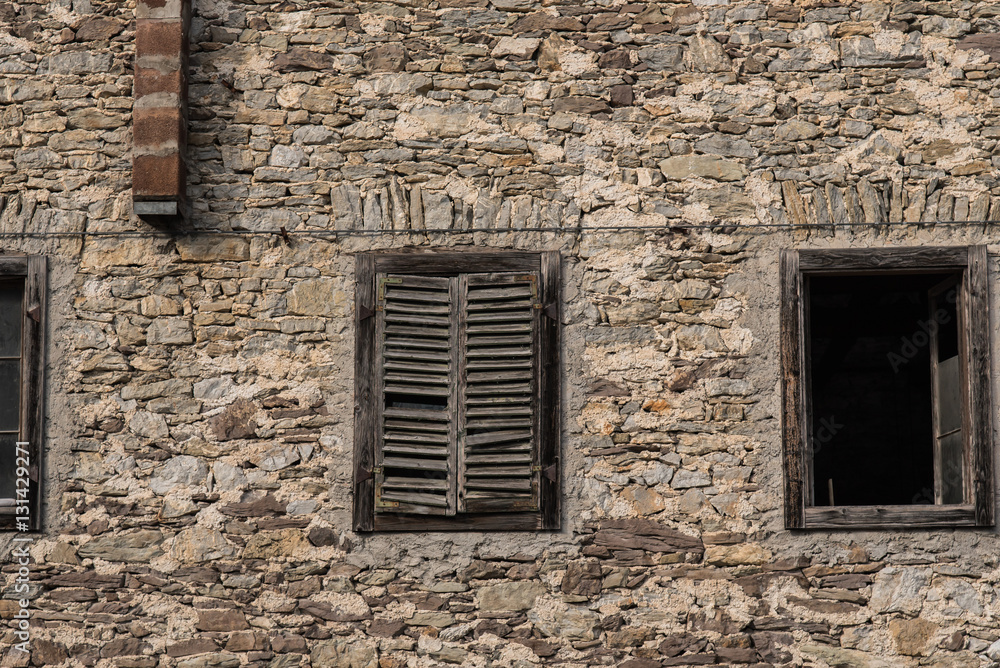 Old building in Northern Italy broken down and worn with windows and old stone facade