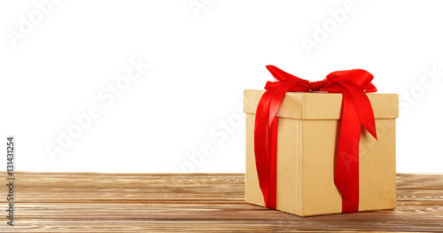 Gift box with ribbon bow on wooden table