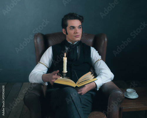 Retro victorian dickens style man reading book by candlelight. photo