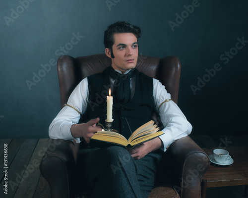 Obraz na płótnie Retro victorian dickens style man reading book by candlelight. w salonie
