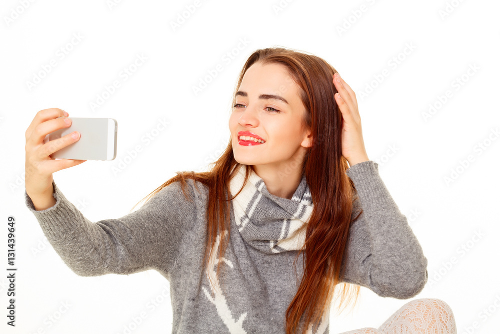 Happy young beautiful girl making selfie on the phone in sweater