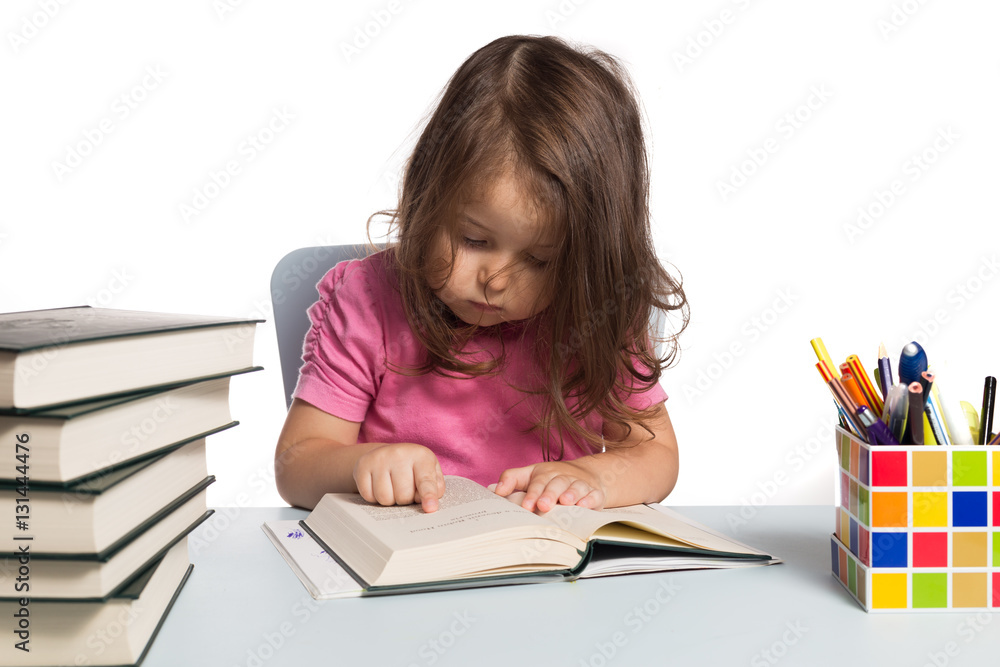 Small girl in pink t-shirt learning how to read at her desk Small girl in pink t-shirt learning how to read at her desk