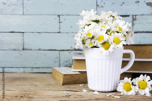 Fototapeta Naklejka Na Ścianę i Meble -  Fresh daisy flowers in white cup on wooden table