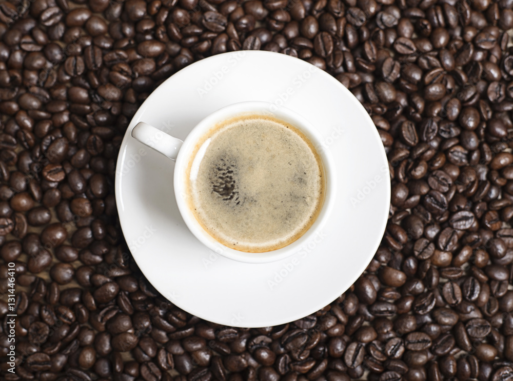 Close-up view from above of a cup of coffee over coffee beans. Texture. Close-up view from above of a cup of coffee over coffee beans. Texture.