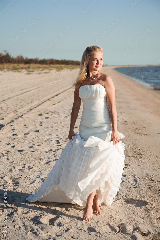 Bride walking along sea coast wearing beautiful wedding dress Bride walking along sea coast wearing beautiful wedding dress