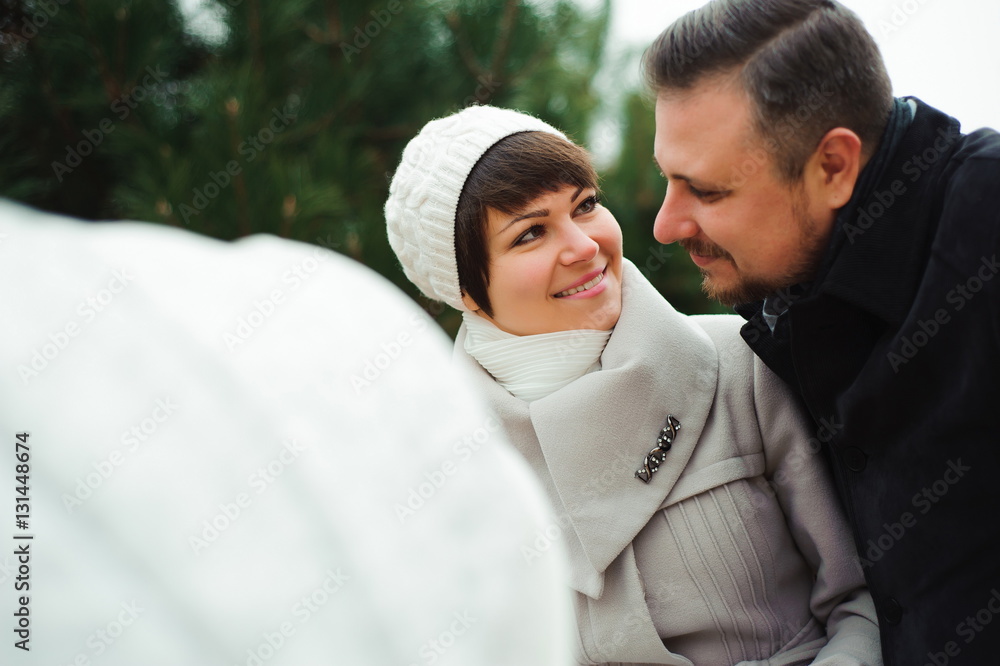 Fototapeta premium Family walk in the autumn park with a pram. Mom, dad and baby ou