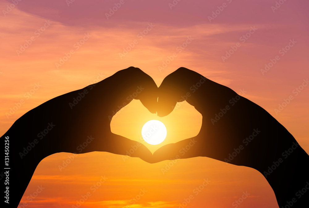 Naklejka premium sunset in the middle silhouette hands heart shape 