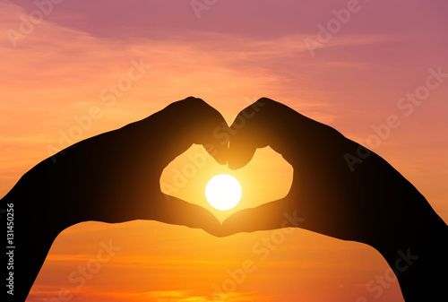 sunset in the middle silhouette hands heart shape 