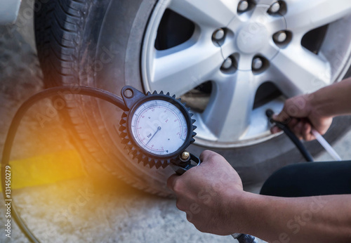 Close up mechanic inflating tire and checking air pressure with gauge pressure   
