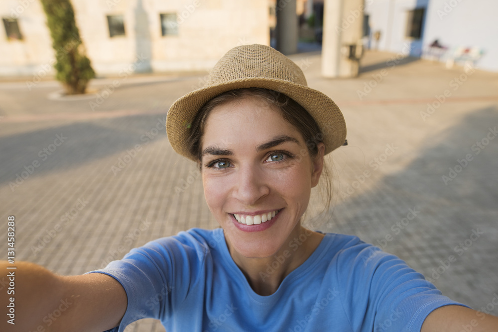 End result selfie picture of a beautiful young woman smiling, while wearing a hat and a blue tshirt