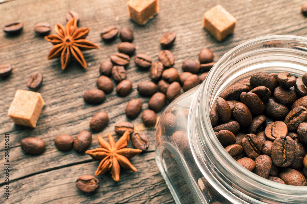 Coffee beans into glass jar table with sugar and anise Coffee beans into glass jar table with sugar and anise