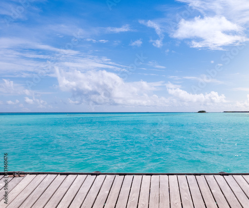 Wooden floor with sea and blue sky background.