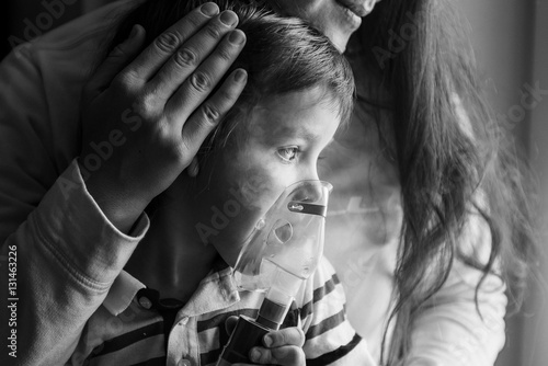 Young woman with son doing inhalation a nebulizer at home