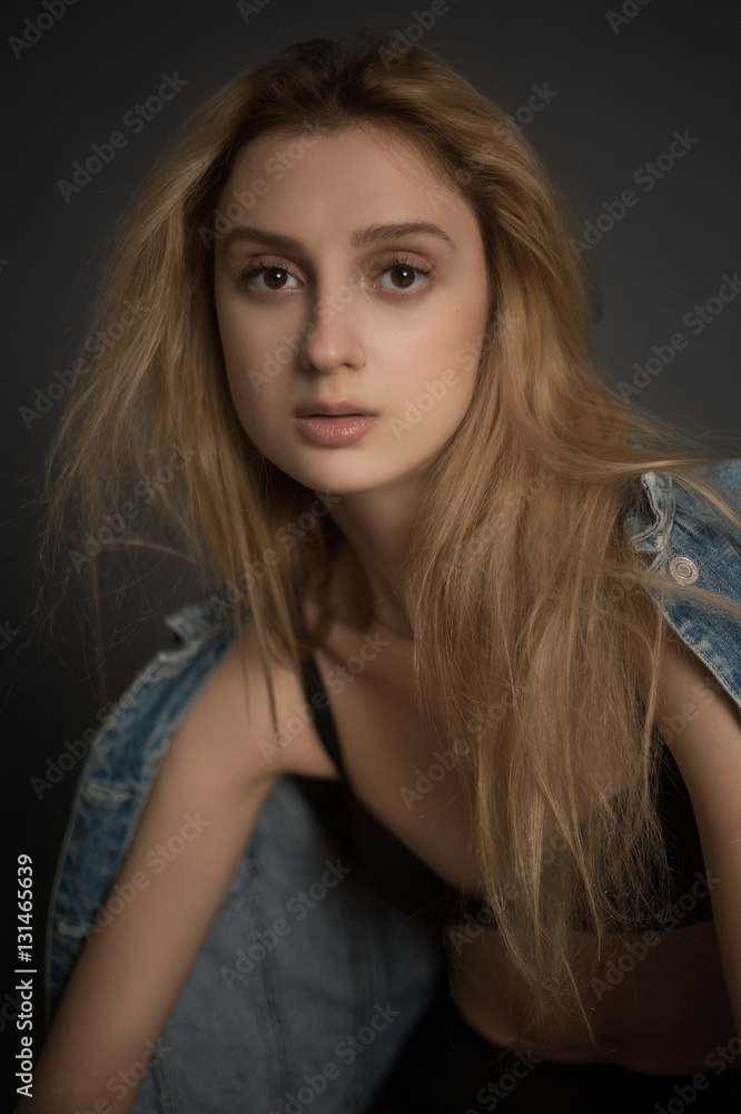 Portrait of sad beautiful young blonde woman in bra and jeans jacket