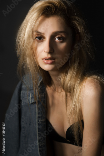 Portrait of sad beautiful young blonde woman in bra and jeans jacket