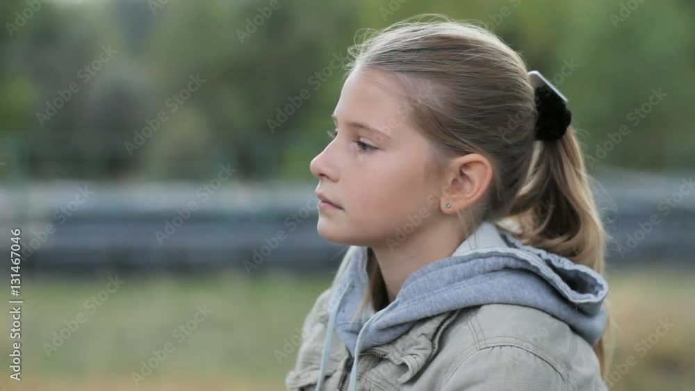 Sad pensive young girl looking straight ahead then head down. Kid girl serious face portrait outdoor. Sad pensive young girl looking straight ahead then head down. Kid girl serious face portrait outdoor.