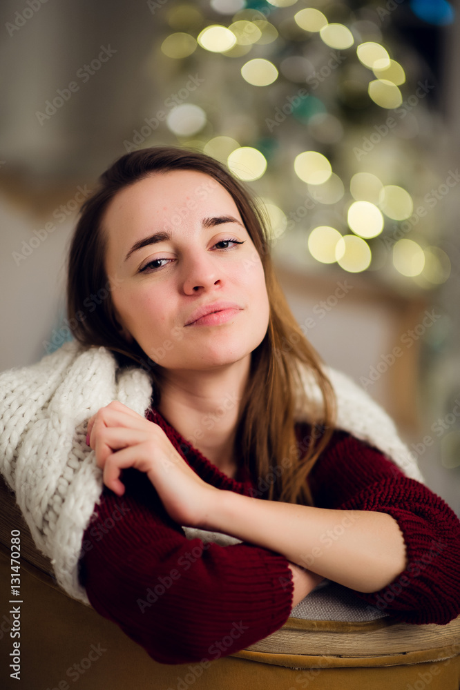 Smiling beautiful woman sitting over Christmas tree on the background Smiling beautiful woman sitting over Christmas tree on the background
